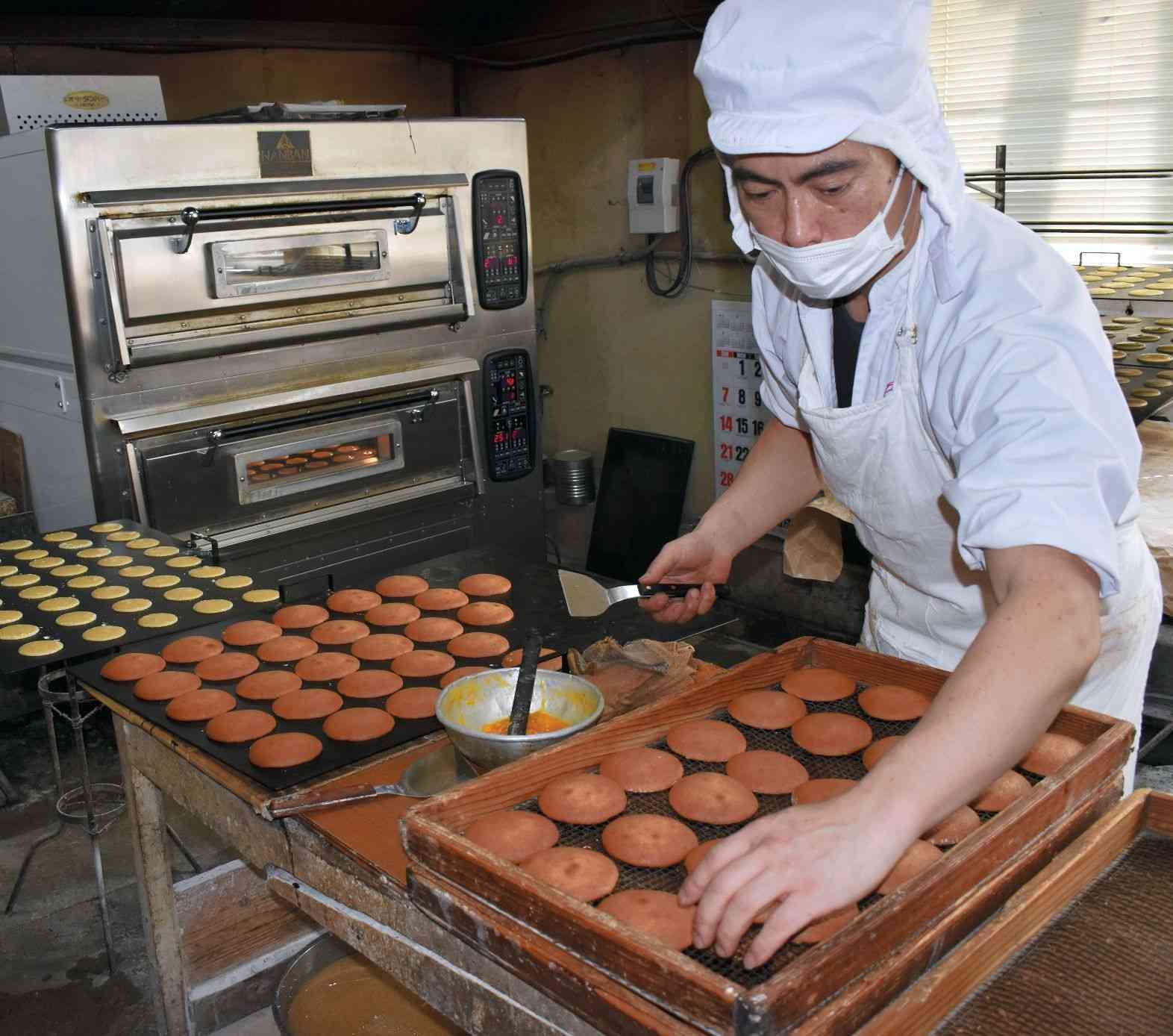 丸ぼうろをどのように焼くか難しいという。手早く仕上げの作業をする職人＝佐賀市の鶴屋