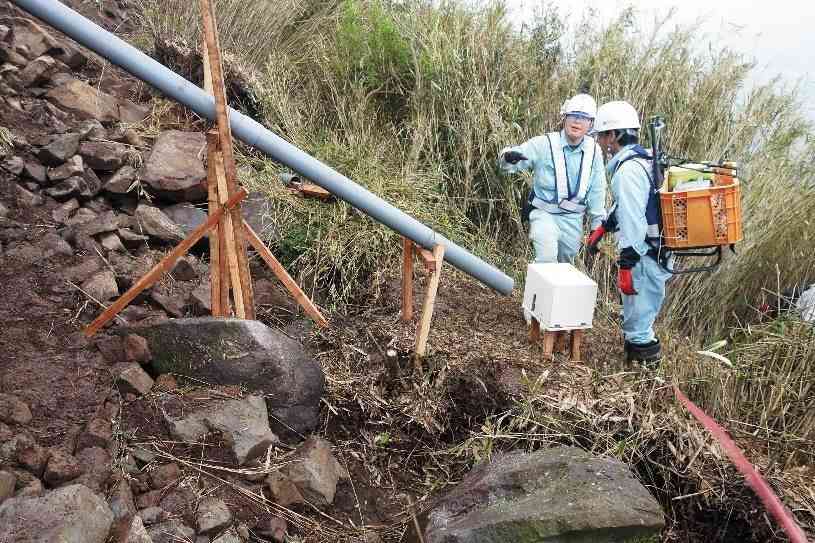 大規模崩壊した阿蘇外輪山の斜面の亀裂に、「地盤伸縮計」を設置する県地質調査業協会の会員ら＝２０１６年４月、南阿蘇村（同協会提供）