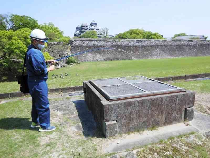 熊本城内の井戸に釣り糸を垂らして水位や深さを測定する中田卓さん。写真は二の丸広場の井戸＝４月７日、熊本市中央区