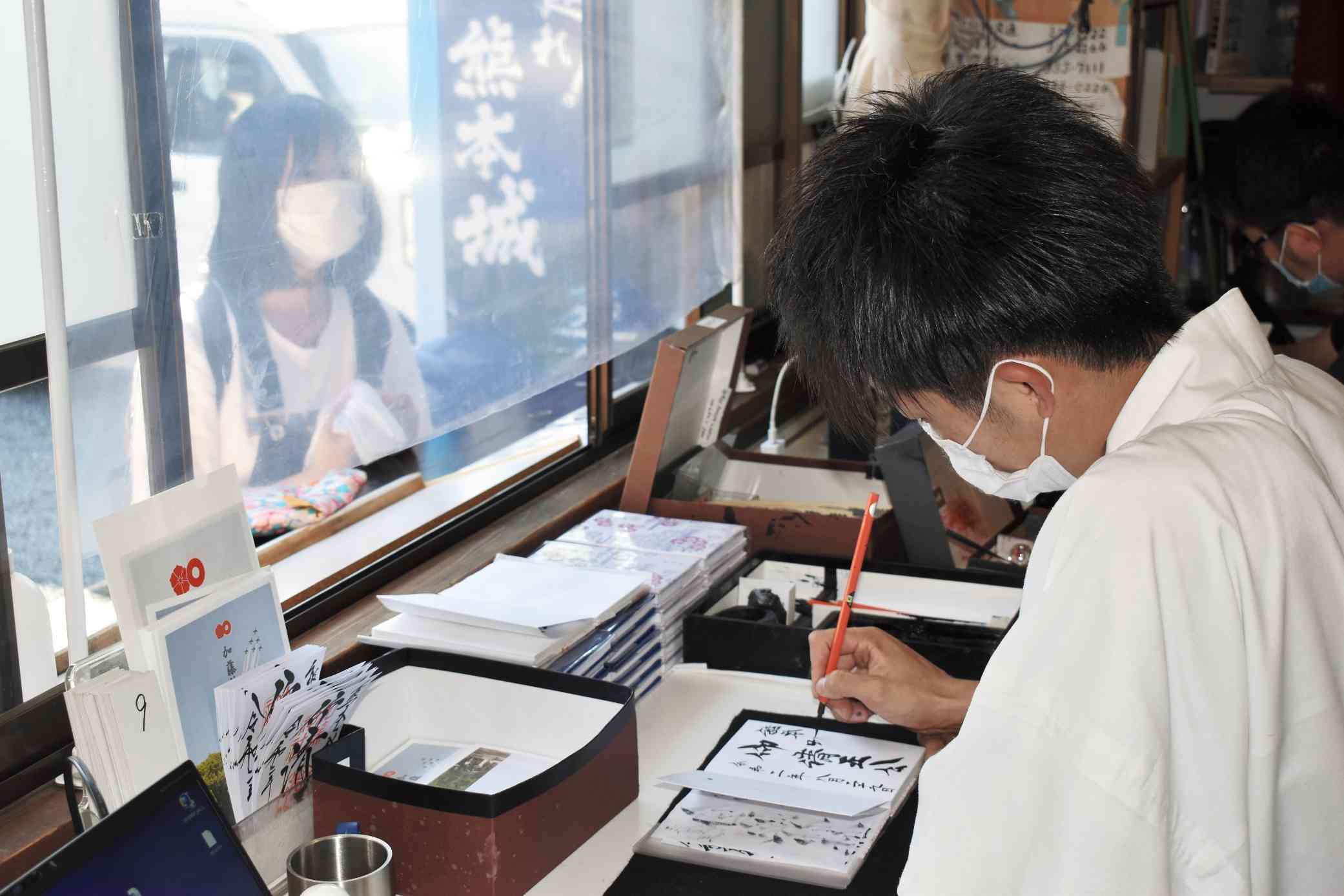 加藤神社の御朱印帳記帳所で、受け付けた御朱印帳に墨書する神職