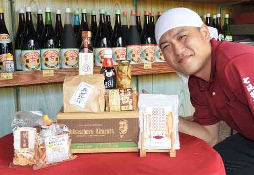 小国町の土産物を詰め合わせたセットと、七福醤油店の大塚知寛さん＝同町