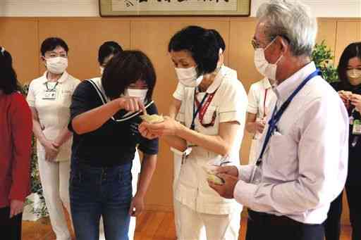 医療従事者にマスクホルダーに込めたこだわりについて説明する利用者（左）＝熊本市北区