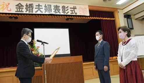 本田清悟・熊日事業局長（左）から代表して表彰される中尾光成さん、香さん夫婦＝玉東町