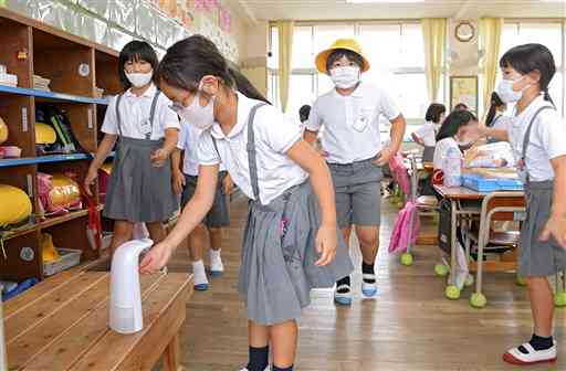 教室内で手指の消毒をする西里小の児童＝１３日午前、熊本市北区（小野宏明）