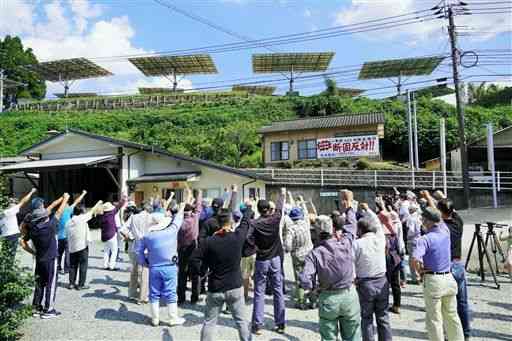 菊池市内の業者が建設している太陽追尾型発電施設（写真上）に向け、「絶対反対」とシュプレヒコールを繰り返す住民たち＝同市