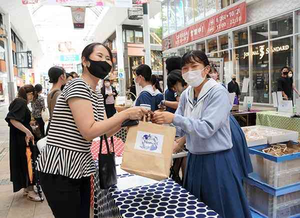 食品ロス削減イベントで菓子を販売する熊本学園大付属高の生徒（右）ら＝７月、熊本市中央区の下通アーケード