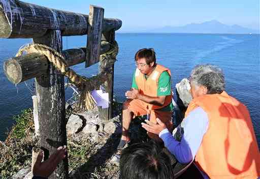 風流島の鳥居に新しいしめ縄を飾り付け、手を合わせるノリ漁師たち＝宇土市