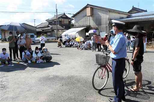 氷川町若洲地区であった防災教室で、八代署員から自転車の乗り方について学ぶ技能実習生たち（同町提供）