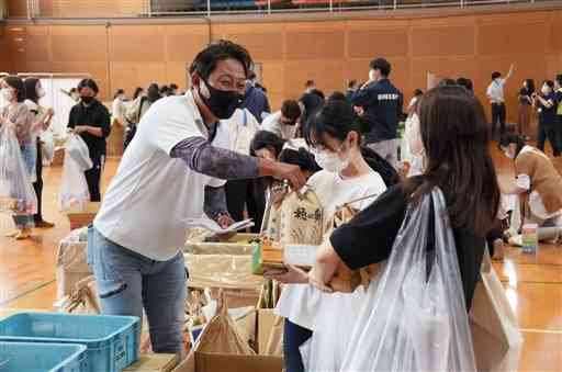 食品や日用品の無料配布会でコメを受け取る学生たち～８日、玉名市の九州看護福祉大
