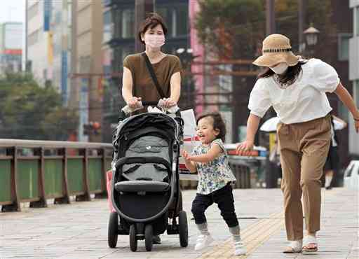 １３日の最高気温が全国１位となった熊本市の繁華街を半袖姿で歩く家族連れ＝１３日午後、同市中央区（小野宏明）