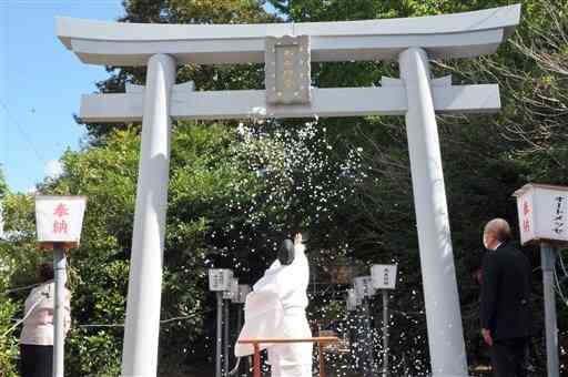 再建された鳥居のおはらいをする木山神宮の禰宜の矢田幸貴さん（中央）＝益城町