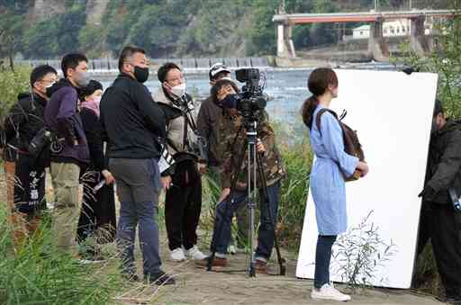 球磨川河川敷で映画の撮影に臨む、主演女優の内田慈さん（右）や遠山昇司監督（左から５人目）＝八代市