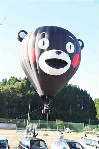 子どもたちを乗せ旧鶴城中校庭から飛び立ったくまモンの熱気球＝２３日、山鹿市