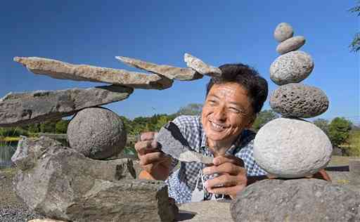 いろいろな形の石を使って、「ロックバランシング」の作品を作る佐藤清貴さん＝９日、嘉島町の浮島神社