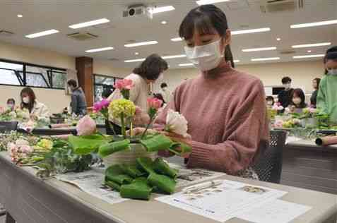 肥後花市場が開いた制作体験教室で、県産の花をアレンジメントに仕上げていく県立大の学生＝１０日、熊本市東区