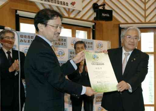 全国初の「環境首都」の称号を獲得しを表彰式で認定証を受け取る宮本勝彬市長（右）＝２０１１年５月、水俣市のもやい館