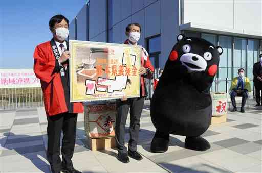 日本酒「絆舞」の完成セレモニーで、義援金を受け取る県東京事務所の内田清之所長（右）＝５日、東京・羽田空港