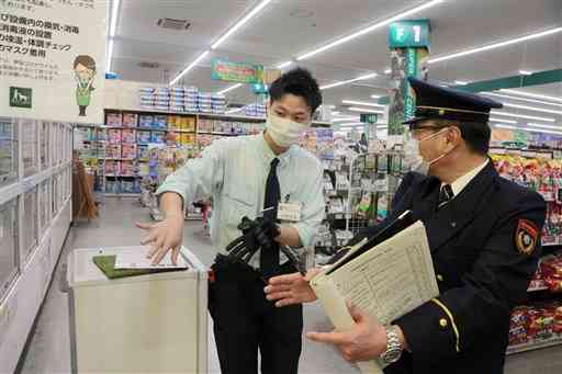 店内の防火管理体制を確認する西消防署員（右）＝熊本市西区