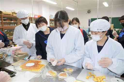 上天草バザールで販売するチーズケーキの包装を試す松島中の生徒＝上天草市