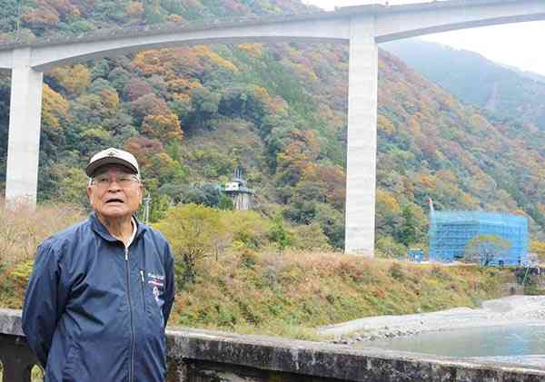 川辺川に架かる頭地橋の上で「村を翻弄するのは終わりにしてほしい」と話す犬童雅之さん。奥は頭地大橋＝１１日、五木村