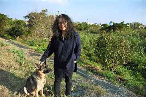 カリフォルニアから連れて来た愛犬クレイマーと自宅近くの坪井川遊水地に立つ伊藤比呂美さん＝熊本市中央区