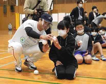 キャッチボール教室で児童にボールの握り方を教える高橋由伸さん（左）＝球磨村