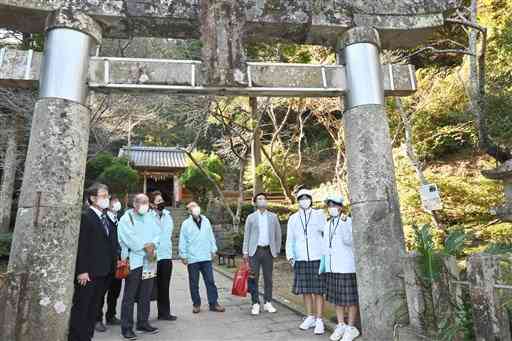 河浦中のボランティアガイド（右２人）から説明を受ける八代市東陽町の視察団＝天草市