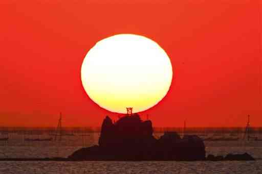 夕日と重なり、シルエットになって浮かび上がった風流島＝１９日午後５時ごろ、熊本市南区海路口町の緑川河口から撮影