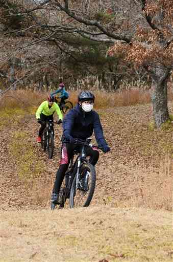 瀬の本の牧野を自転車で走るツアー参加者＝南小国町