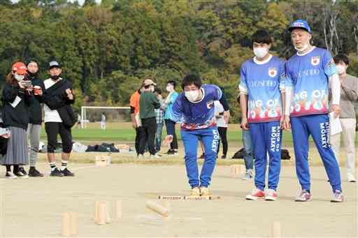 棒を投げてピンを倒す芸人チームの（中央左から）森田哲矢さん、カナイさん、みなみかわさん＝大津町
