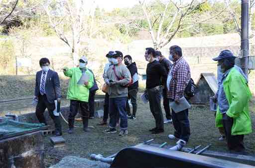 ホタルが生育しやすい環境づくりについて説明する岱明町ホタルの里保全隊のメンバー（黄色のユニフォーム）ら＝玉名市