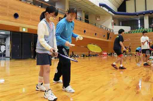 子どもたちにフォームなどを教える再春館バドミントン部の選手（左から２人目）＝合志市