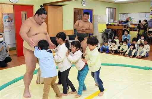 大栄翔関（左）と相撲を取る高森幼稚園の園児たち＝高森町