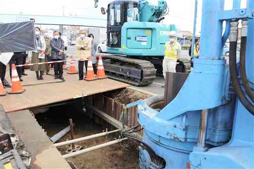 地下に鋼製の矢板を設置する工事を視察する技術検討委のメンバーら＝熊本市南区
