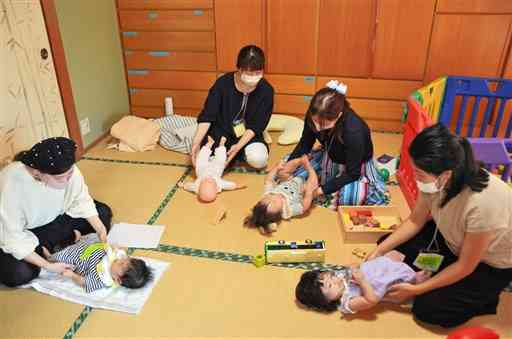 縁側ｍｏｙａｉのイベントで、赤ちゃんのマッサージについて学ぶ母親ら＝熊本市南区