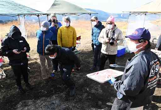 バーベキューに使うあか牛のもも肉について、地元の住民（右）から説明を受けるツアー参加者＝阿蘇市