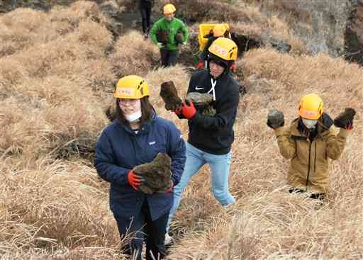 杵島岳の登山道を修復するため、石を運ぶ参加者たち＝阿蘇市