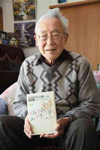 再出版された「平川唯一のファミリーイングリッシュ　カムカムエヴリバディ」を手にする熊本大名誉教授の福田昇八さん。唯一さんの次男、洌（きよし）さんと共に編者を務めた＝熊本市北区