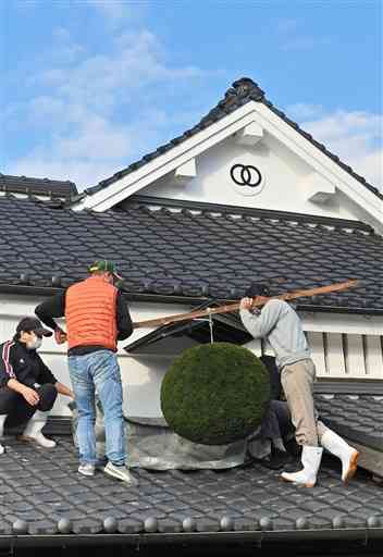 屋根に新しい杉玉を取り付ける通潤酒造の従業員ら＝山都町