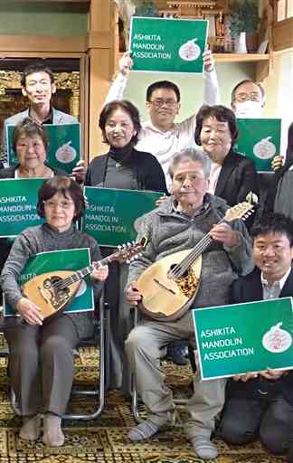 会長の坂本純男さん（前列中央）を励まそうと集まった芦北町マンドリン協会のメンバー。同左は妻まり子さん＝同町