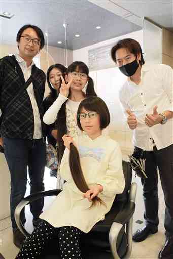 ヘアドネーションのために髪を切った前村史奈さん（手前）と家族（後方左の３人）、美容師の甲斐秀康さん（右）＝菊陽町