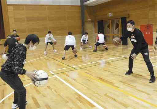 子どもたちにドリブルの基本を教える熊本ヴォルターズの柿内輝心選手（右）＝芦北町