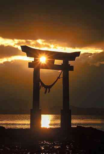 雲間から顔をのぞかせ、永尾剱神社の海中鳥居の間に沈む夕日＝１８日午後４時５０分ごろ、宇城市不知火町（池田祐介）