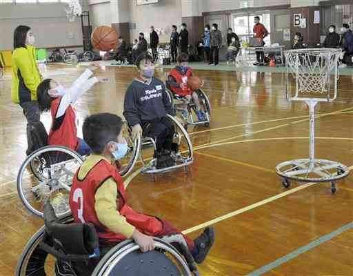 安尾笑選手（中央）の指導を受けながらシュートを体験する小学生たち＝県身体障がい者福祉センター