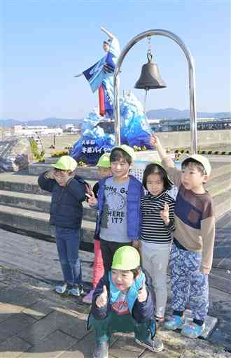 牛深港フェリー乗り場に設置された船鐘を鳴らす園児たち＝天草市
