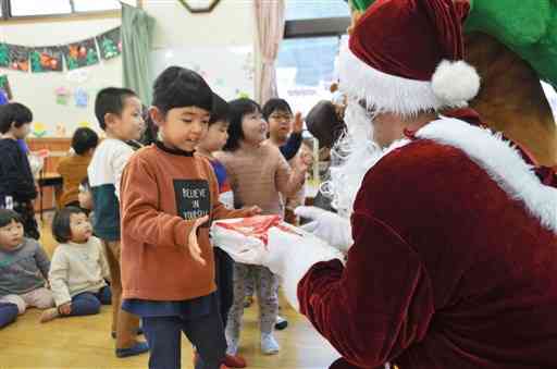 サンタクロースにふんした南小国町商工会青年部のメンバーからプレゼントをもらう園児＝同町