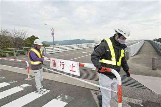 牛深ハイヤ大橋の通行止めバリケードを取り外す委託業者＝２４日午前１０時、天草市