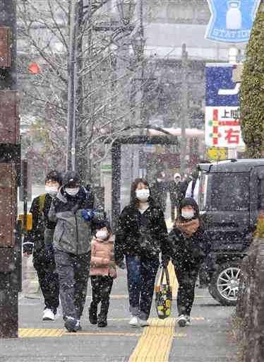 雪が舞う中、県立総合体育館前を歩く人たち＝２６日午後１時すぎ、熊本市西区（後藤仁孝）