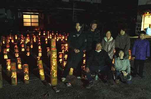 元号を透かし彫りにした竹灯籠を製作した前田孝一さん（前列右から２人目）＝菊陽町