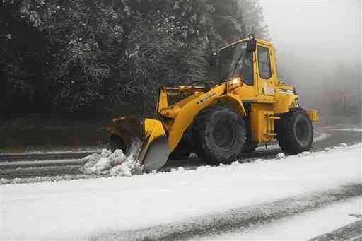 国道２６５号で除雪作業をする地元建設会社の重機＝６日午前８時４５分ごろ、阿蘇市